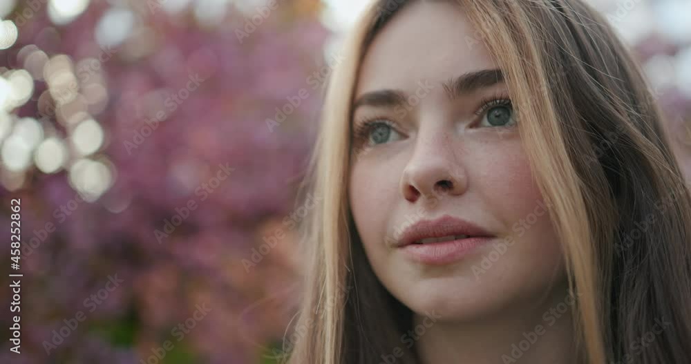 Portrait Face of Gorgeous Young Lady with Beautiful Green Eyes looking ahead. Attractive Caucasian Girl having Cute Appearance with Long Eyelashes. Standing outdoors. Enjoys Nature. Flowering Trees. Portrait Face of Gorgeous Young Lady with Beautiful Green Eyes looking ahead. Attractive Caucasian Girl having Cute Appearance with Long Eyelashes. Standing outdoors. Enjoys Nature. Flowering Trees.