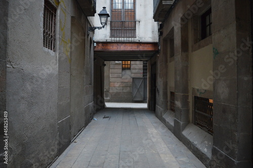Narrow Street with old buildings leading to a bright area in Barcelona  Spain