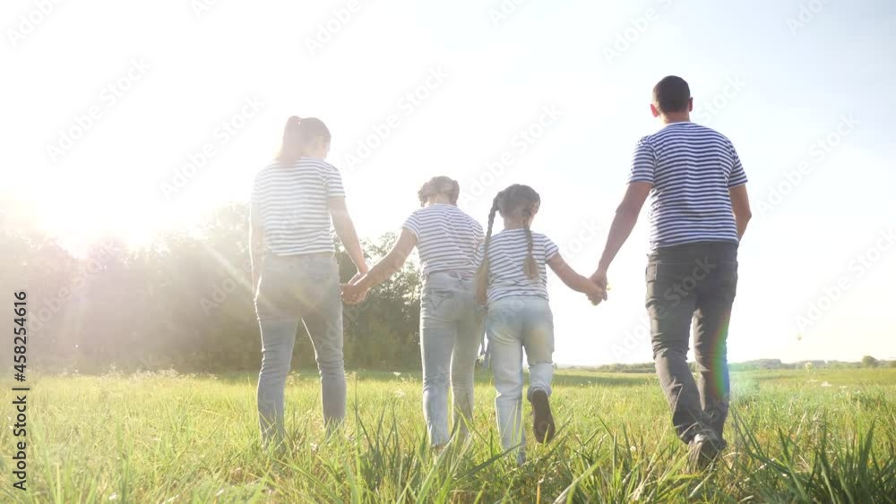 happy family walking in the park. friendly family kid dream concept. mom dad and children walk in the park on green grass outdoors. happy lifestyle family with their backs walking in the park in happy family walking in the park. friendly family kid dream concept. mom dad and children walk in the park on green grass outdoors. happy lifestyle family with their backs walking in the park in