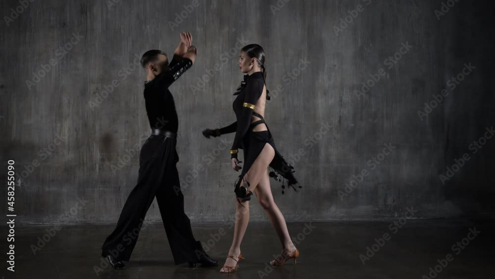 The young millennial dance ballroom couple in black dress dancing in sensual pose on studio background. Professional dancers dancing latino. Hobby dance concept. Human emotions - love and passion The young millennial dance ballroom couple in black dress dancing in sensual pose on studio background. Professional dancers dancing latino. Hobby dance concept. Human emotions - love and passion