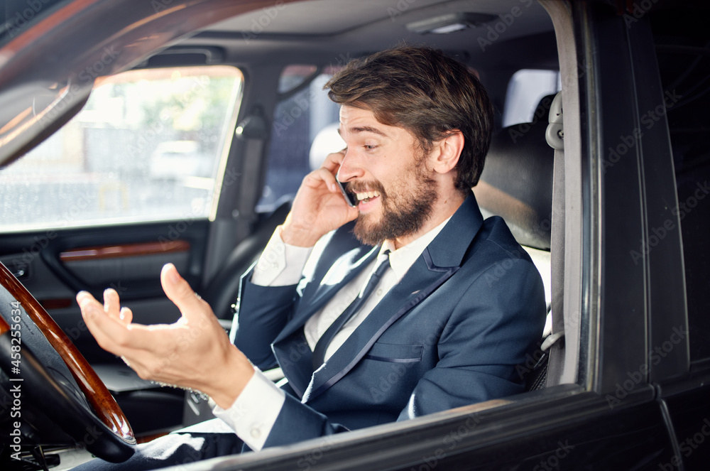 bearded man in a suit in a car a trip to work communication by phone