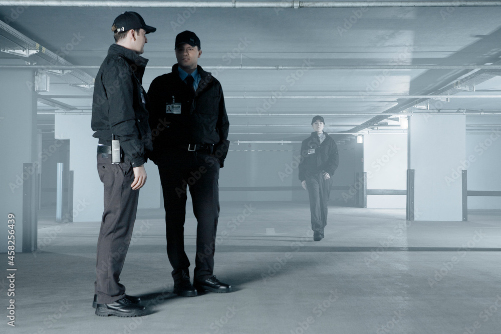 Security guards talking in empty parking garage Security guards talking in empty parking garage