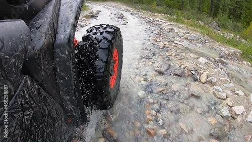 The wheel of the buggy rides on a rocky riverbed