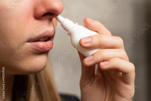 The girl treats nasal congestion. close-up. nasal spray.