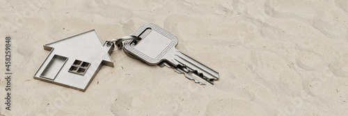 Zwei verlorene Schlüssel mit Haus liegen im Sand photo