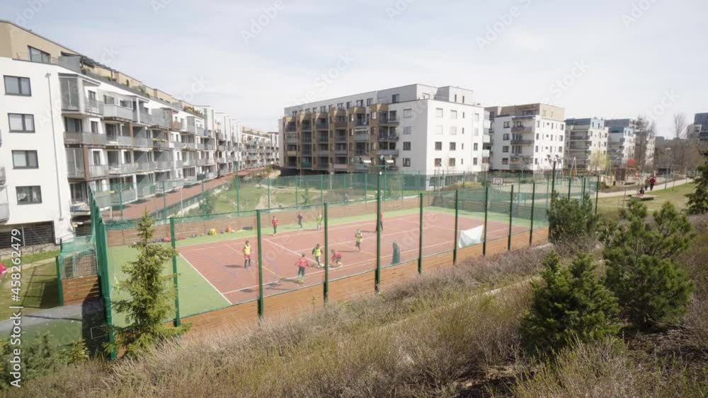 Boys play basketball at a court in an apartment complex area - top view from distance - apartment buildings in the background Boys play basketball at a court in an apartment complex area - top view from distance - apartment buildings in the background
