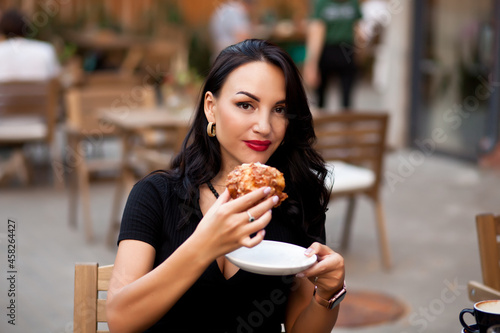 Beautiful woman drinking coffee in a cafe and eating croissant