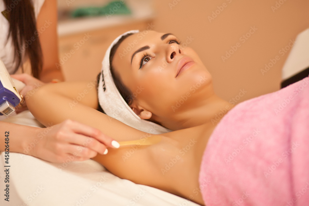 Obraz premium Beautician waxing female armpits in spa center