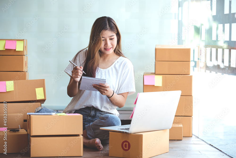 Small start-up business owners using computers at work, freelancers, saleswoman, checking production orders. Pack products for delivery to customers Small start-up business owners using computers at work, freelancers, saleswoman, checking production orders. Pack products for delivery to customers