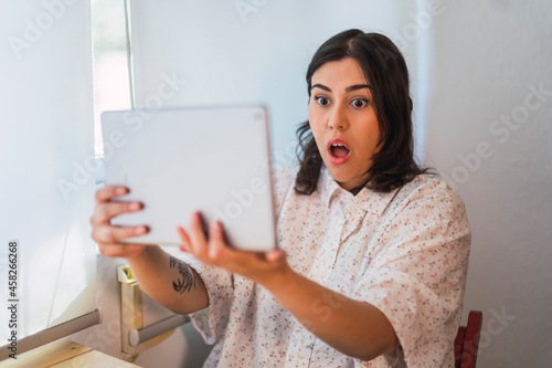Chica joven risueña guapa interactuando con una tablet