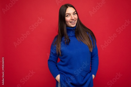 Smiling young beautiful brunette woman with sincere emotions isolated on background wall with copy space wearing casual trendy blue sweater. Positive concept © Ivan Traimak