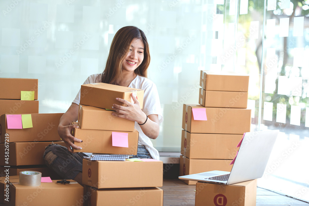 Small start-up business owners using computers at work, freelancers, saleswoman, checking production orders. Pack products for delivery to customers Small start-up business owners using computers at work, freelancers, saleswoman, checking production orders. Pack products for delivery to customers