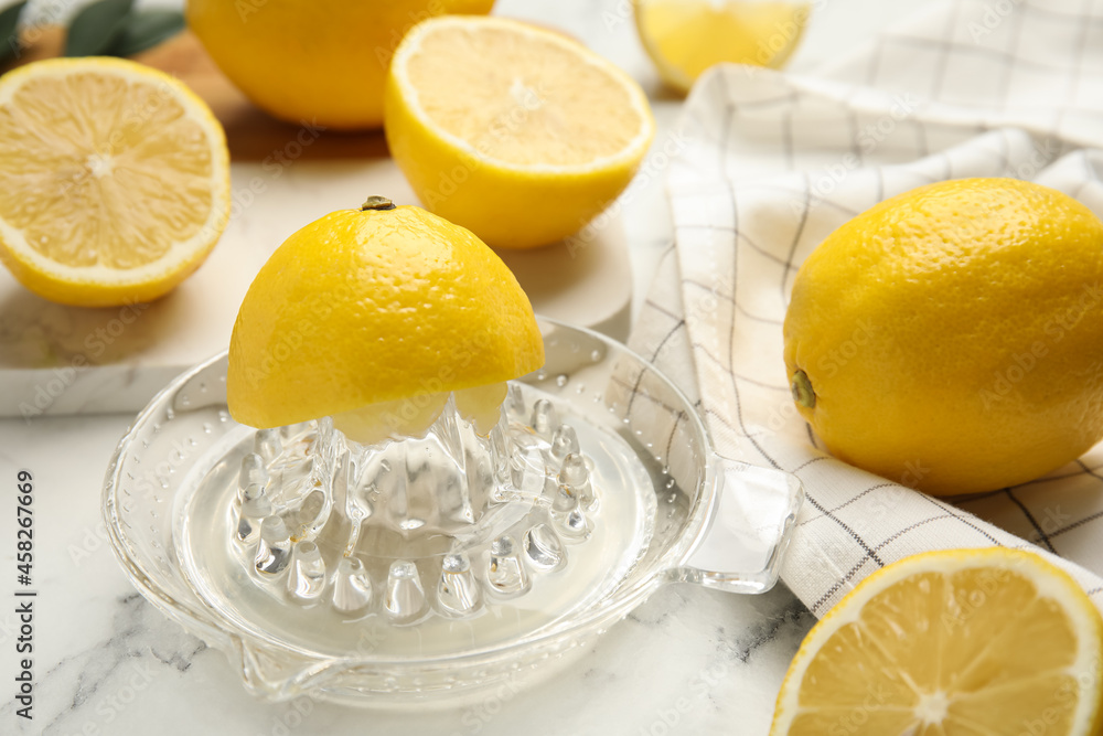 Glass squeezer and fresh lemons on white marble table Glass squeezer and fresh lemons on white marble table