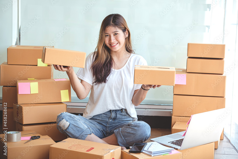 Small start-up business owners using computers at work, freelancers, saleswoman, checking production orders. Pack products for delivery to customers Small start-up business owners using computers at work, freelancers, saleswoman, checking production orders. Pack products for delivery to customers
