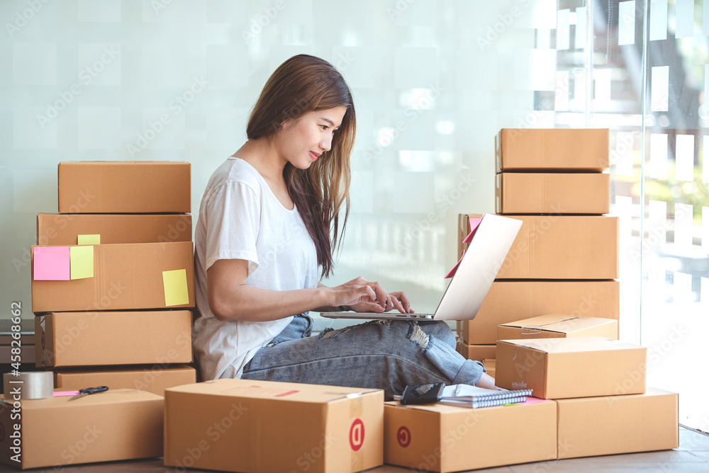 Small start-up business owners using computers at work, freelancers, saleswoman, checking production orders. Pack products for delivery to customers Small start-up business owners using computers at work, freelancers, saleswoman, checking production orders. Pack products for delivery to customers