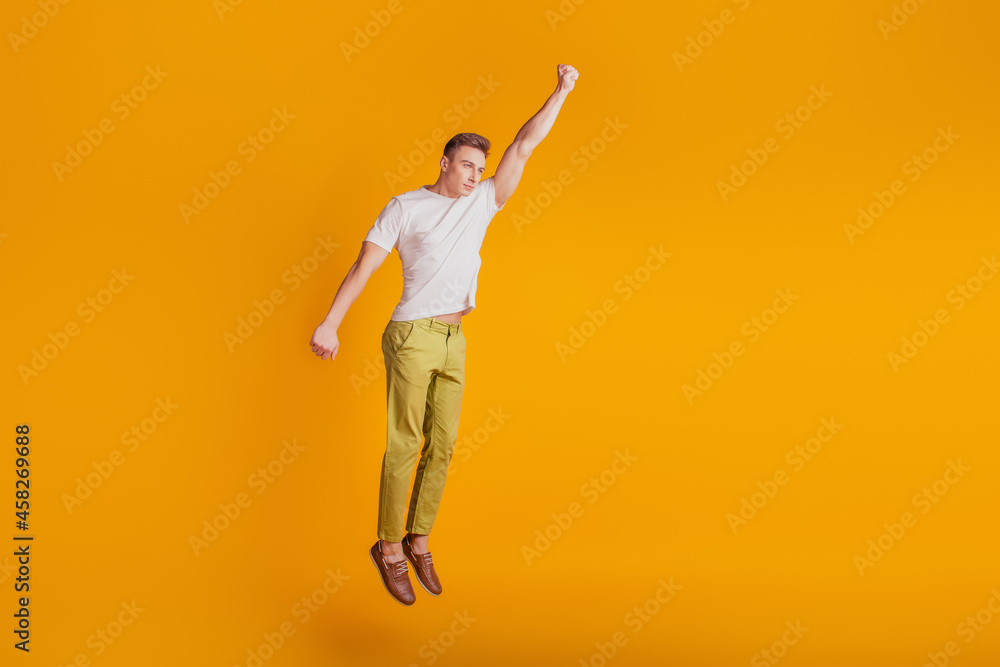 Portrait of crazy superhero guy jump raise fist fly on yellow background Portrait of crazy superhero guy jump raise fist fly on yellow background