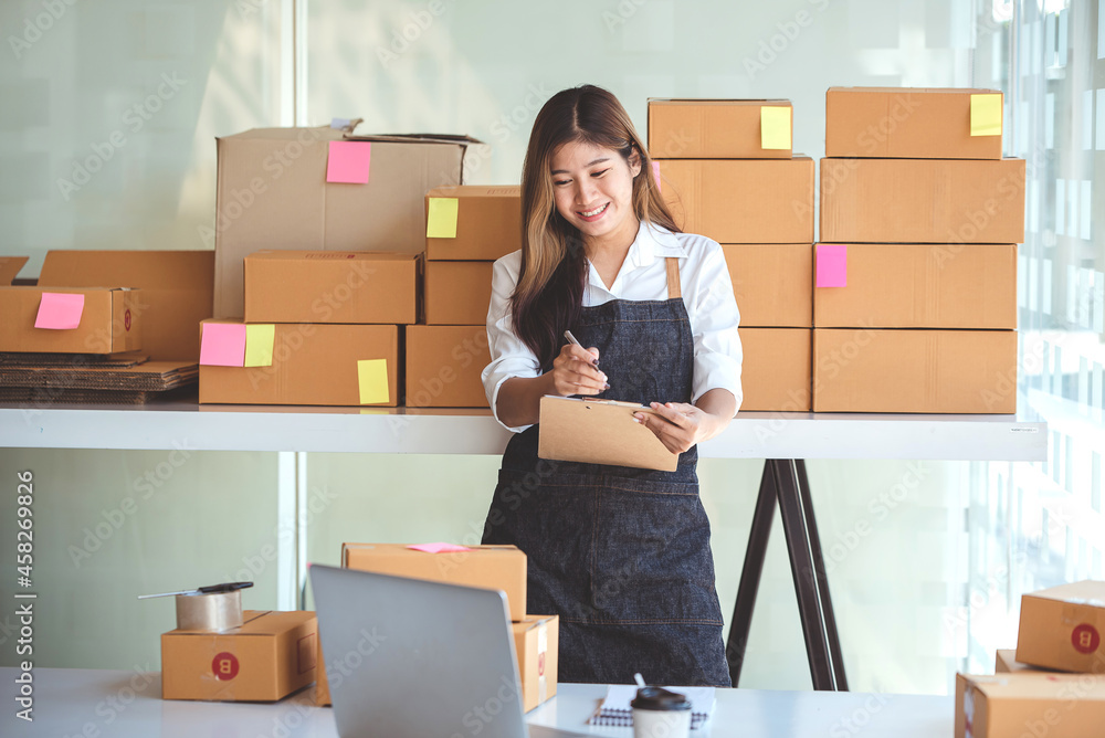Small start-up business owners using computers at work, freelancers, saleswoman, checking production orders. Pack products for delivery to customers Small start-up business owners using computers at work, freelancers, saleswoman, checking production orders. Pack products for delivery to customers