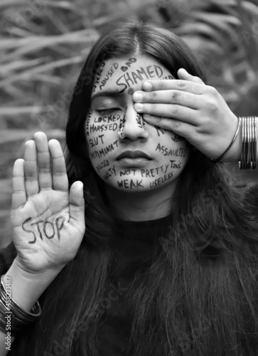 A young woman raising awareness for  International day for the elimination of violence against women by writing a anti violence messages all over her face photo