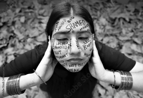 A young woman raising awareness for  International day for the elimination of violence against women by writing a anti violence messages all over her face photo