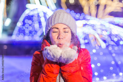 Portrait of young funny attractive woman over snowy Christmas background. Winter holidays and season concept.