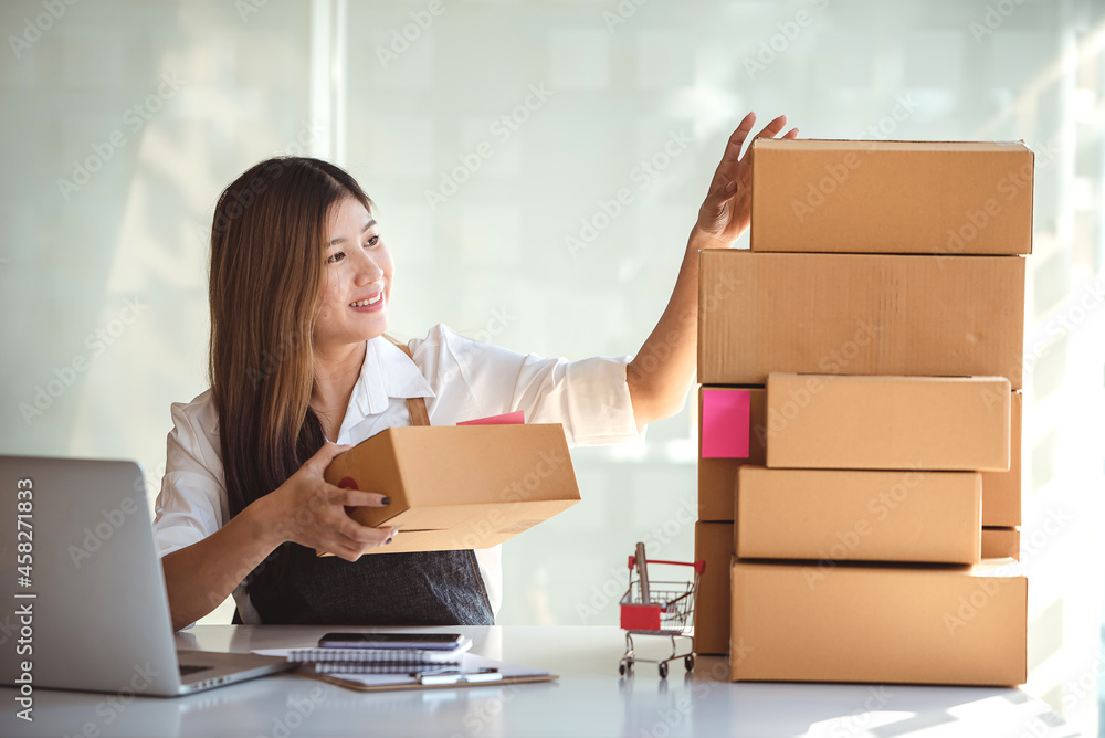 Small start-up business owners using computers at work, freelancers, saleswoman, checking production orders. Pack products for delivery to customers Small start-up business owners using computers at work, freelancers, saleswoman, checking production orders. Pack products for delivery to customers