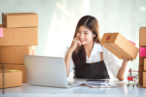 Small start-up business owners using computers at work, freelancers, saleswoman, checking production orders. Pack products for delivery to customers © Daenin