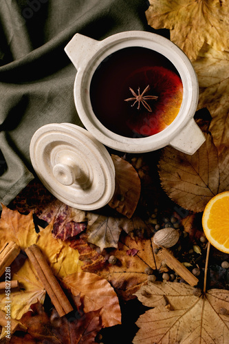 Hot mulled wine with spices and autumn leaves