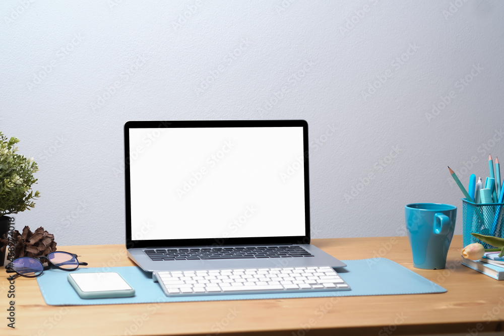 Photo of an empty screen computer laptop with a wireless keyboard putting on a wooden table surrounded by various equipment. Photo of an empty screen computer laptop with a wireless keyboard putting on a wooden table surrounded by various equipment.