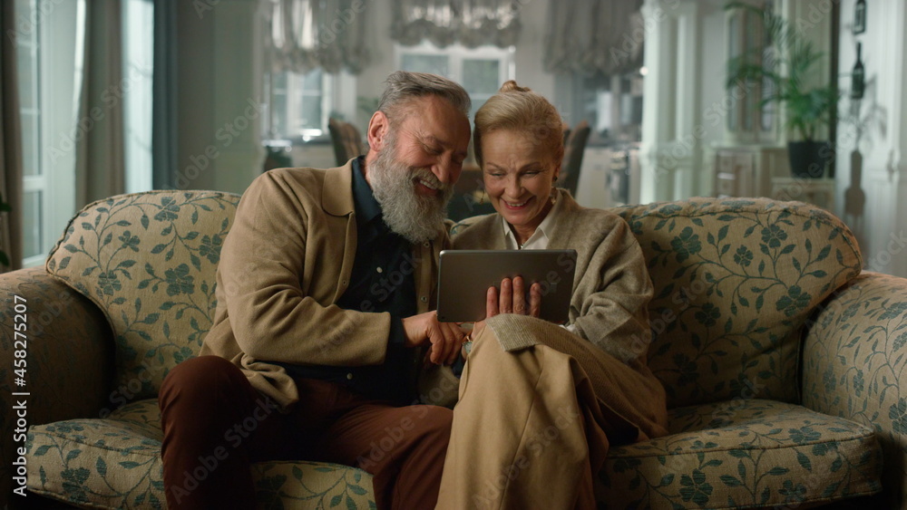 Happy senior old couple talking relaxing using digital tablet computer