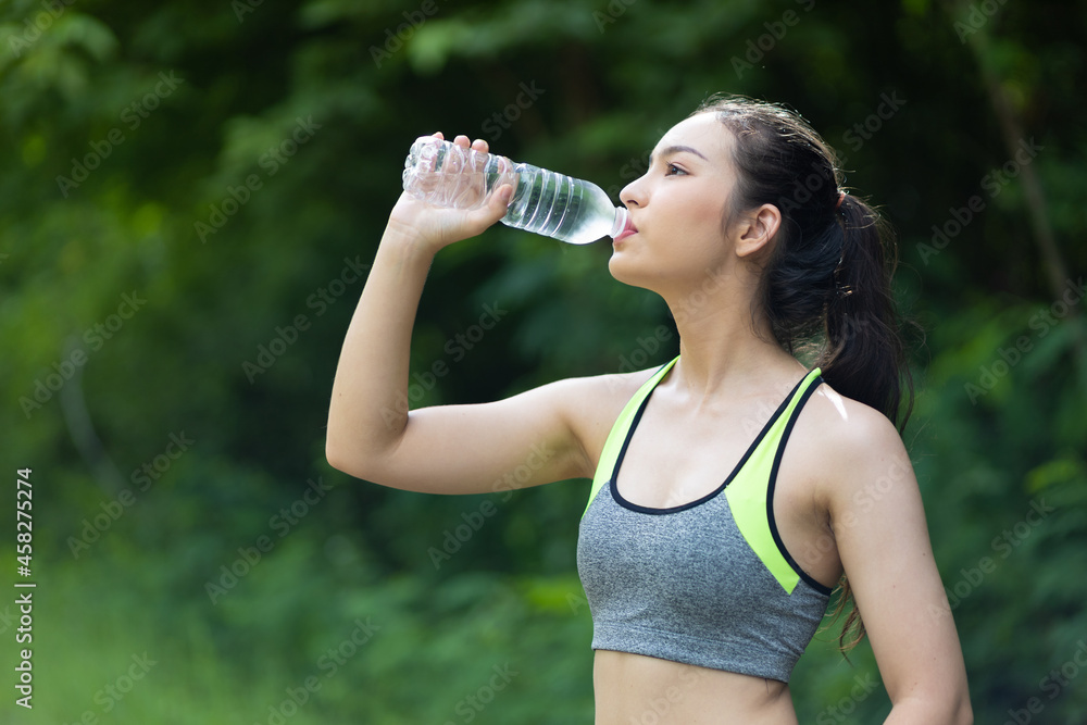 A thirsty Asian female athlete is drinking water after a workout. A thirsty Asian female athlete is drinking water after a workout.