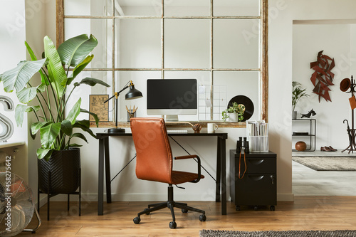 Stylish composition of modern masculine home office workspace interior design with black industrial desk, brown leather armchair, pc and stylish personal accessories. Template. photo