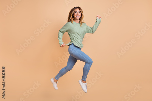 Fototapeta Naklejka Na Ścianę i Meble -  Full length body size photo woman jumping high running cheerful happy isolated pastel beige color background