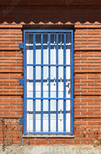 white wooden door protected by blue metal grid door in a red brick wall photo