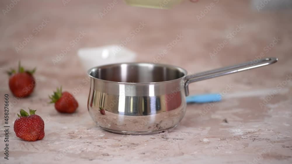 Putting the strawberries and sugar into saucepan.