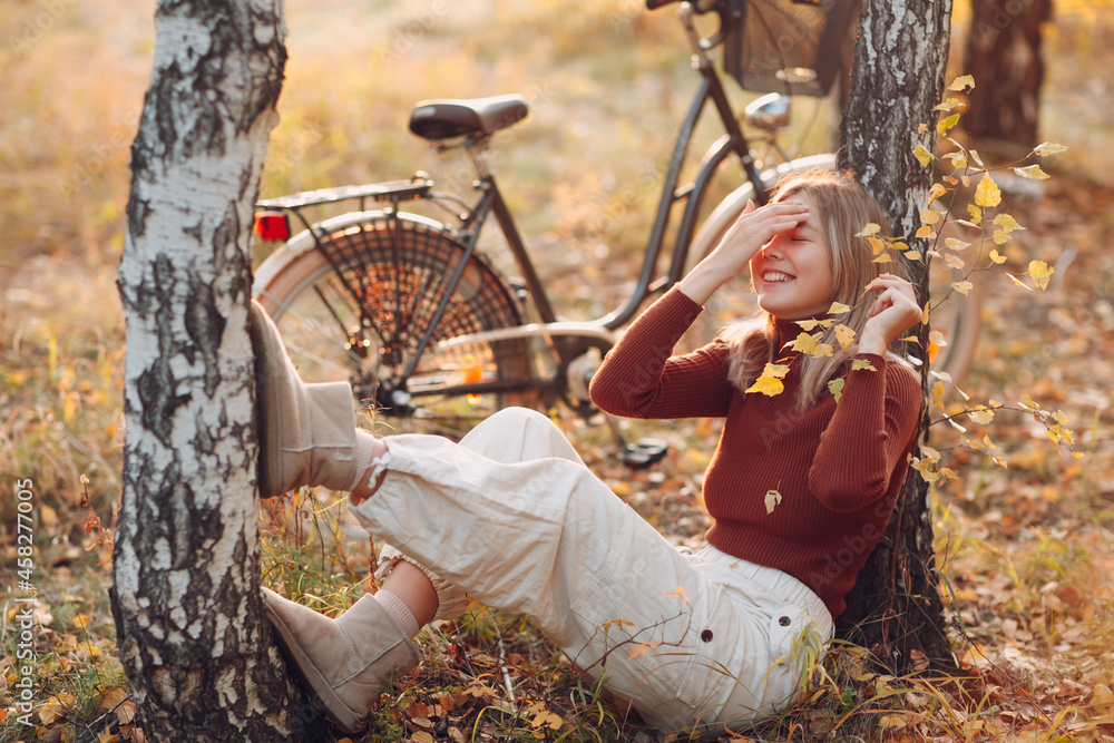 Happy active young smiling woman riding vintage bicycle in autumn park at sunset.