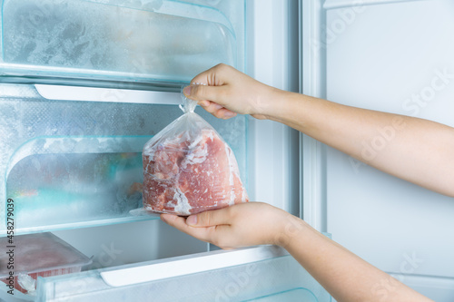 Taking frozen meat from the modern no-frost freezer photo