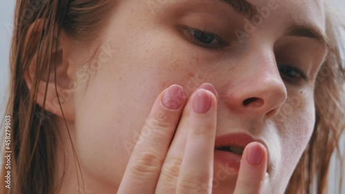 Closeup of attractive female young face with freckles. Young woman applying creme massaging facial skin with nourishing lotion. Concept for health, skincare and wellness. photo