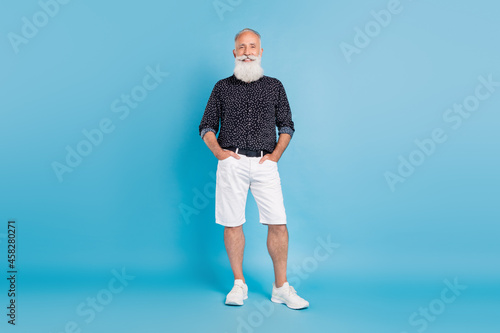 Full length photo of cheerful old man hold hands pockets smile enjoy isolated on pastel blue color background