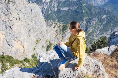 A young girl stands on the top of the mountain and looks down at the gorge, a breathtaking view, Grlo Sokolovo, the gorge that separates Montenegro and Albania photo