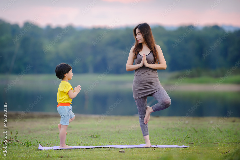 Mother and child doing yoga exercises for healthy and control mind in nature Mother and child doing yoga exercises for healthy and control mind in nature
