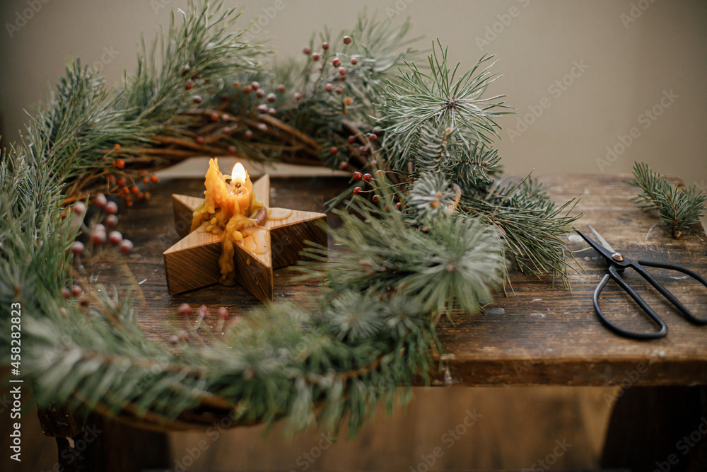 Stylish burning star candle in christmas wreath with spruce branches and berries on rustic wooden background. Merry Christmas! Christmas advent. Holidays in countryside, atmospheric image Stylish burning star candle in christmas wreath with spruce branches and berries on rustic wooden background. Merry Christmas! Christmas advent. Holidays in countryside, atmospheric image