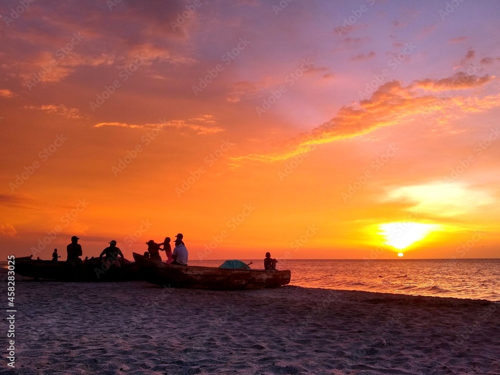 Primer plano de pescadores en la playa, mientras el sol se pone sobre el mar caribe colombiano.