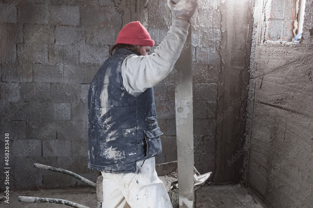 Real construction worker working on a wall inside the new house. Real construction worker working on a wall inside the new house.