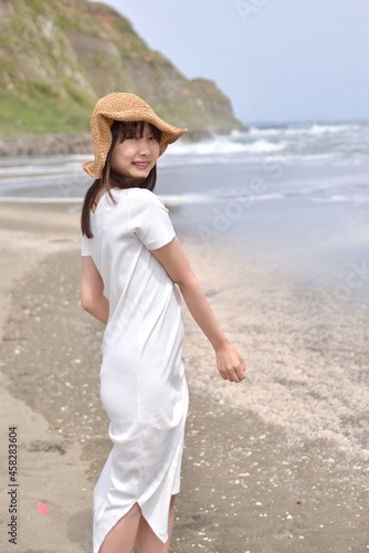 九十九里の海岸でポーズをとる白いワンピースを着た若い女性 