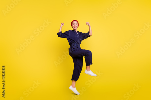 Full length body size view of attractive cheerful lucky girl jumping rejoicing isolated over bright yellow color background © deagreez
