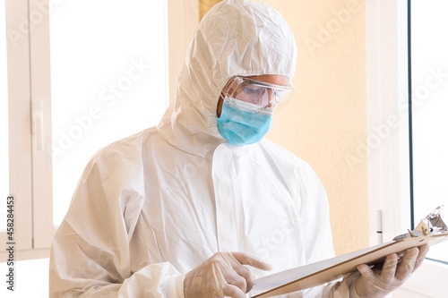 Doctor in PPE suit reading paper while working in clinic photo