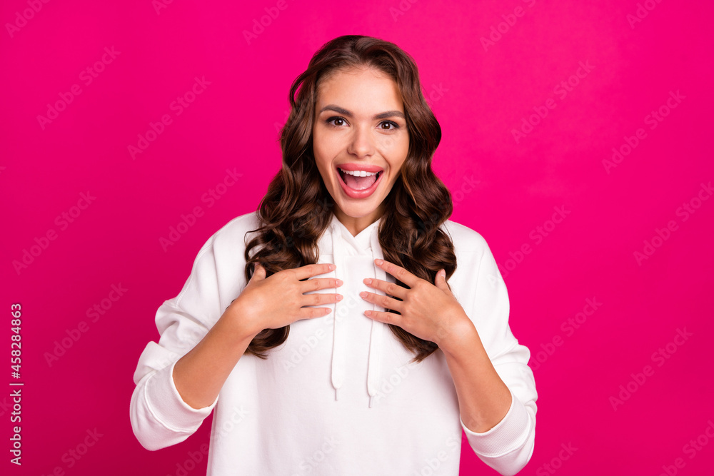 Photo of young excited girl happy positive smile amazed hands touch chest self questioned isolated over pink color background Photo of young excited girl happy positive smile amazed hands touch chest self questioned isolated over pink color background