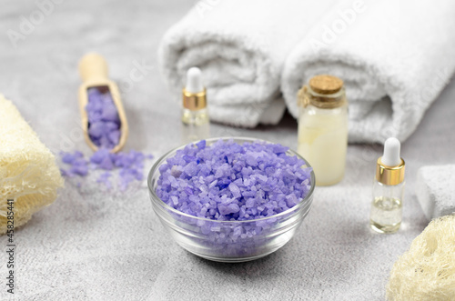 Purple sea salt against the background of essential oils and bath accessories. Spa composition