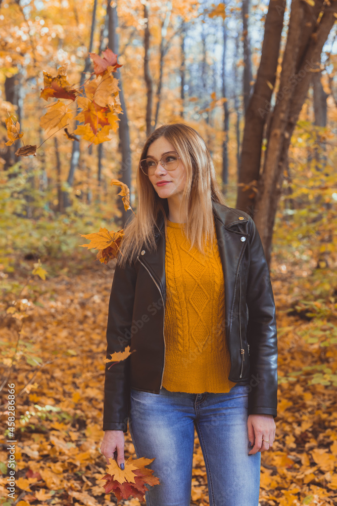 Girl holds fallen leaves and walks in autumn park. Seasonal concept. Girl holds fallen leaves and walks in autumn park. Seasonal concept.