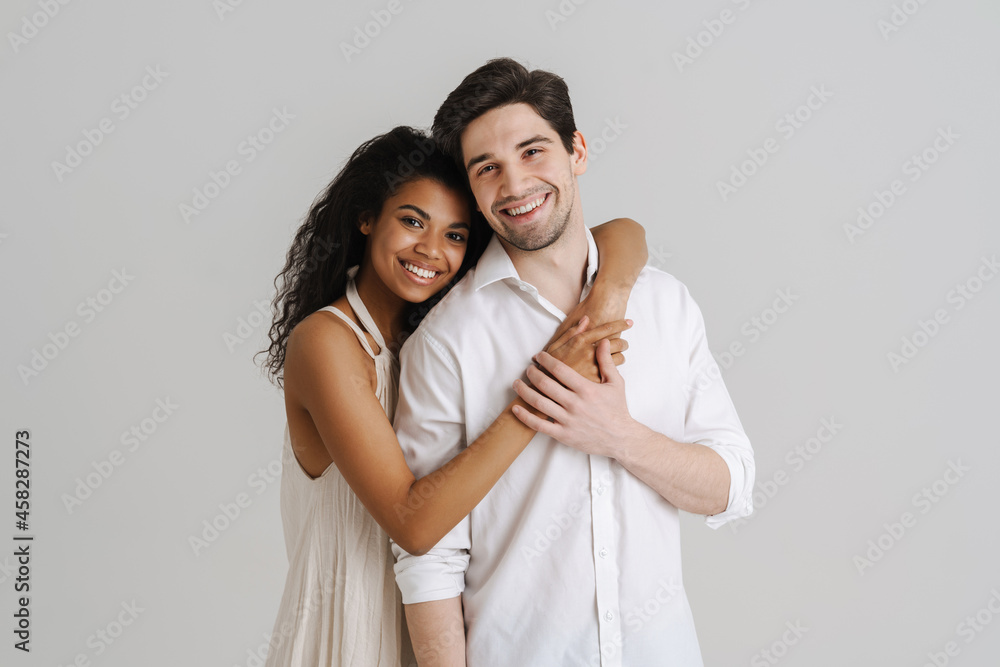 Young multiracial couple hugging and smiling at camera Young multiracial couple hugging and smiling at camera